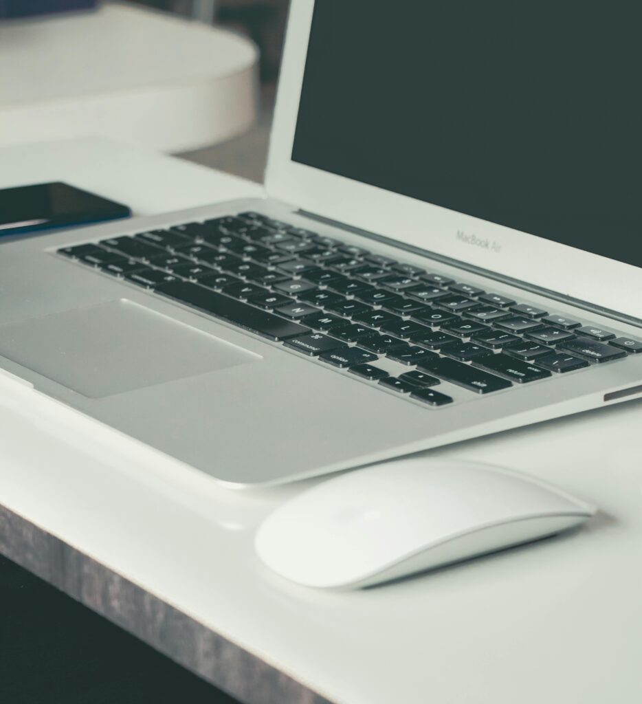 Close-up view of a modern desk setup featuring a laptop and wireless mouse, ideal for productivity.
