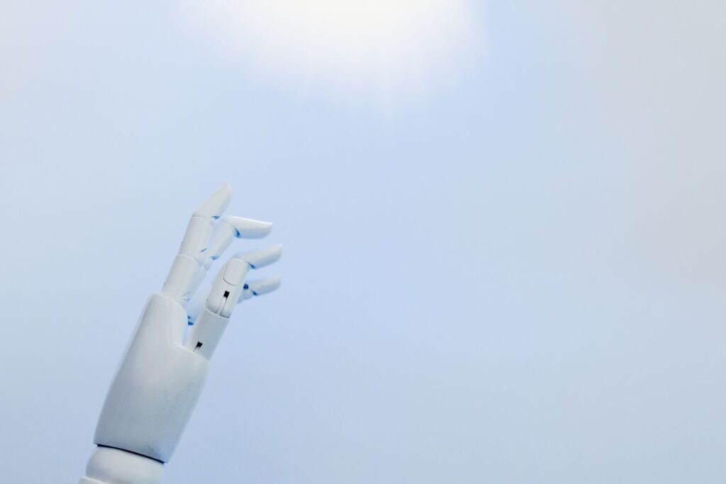 A robotic hand reaching towards a bright light on a white background. AI Tools
